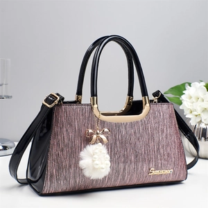 Detail of pink glitter fabric texture and black patent leather trim on a stylish handbag