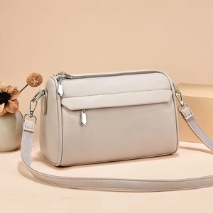 Detail of cream beige lychee leather bag showing multiple silver zippers and hardware