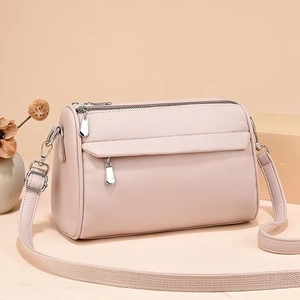 Detailed macro view of the lychee grain leather texture and silver zippers on pink crossbody bag