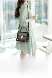 Model wearing a retro contrast leather crossbody bag with elegant gold metal clasp