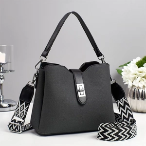Detailed view of gray bucket bag with woven texture and stylish geometric wide strap