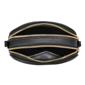 Vue détaillée d'un sac noir en cuir grainé avec trois compartiments à zip doré