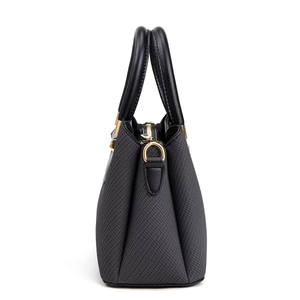 Detail of woven texture handbag with gold D-ring and black leather handle on white background
