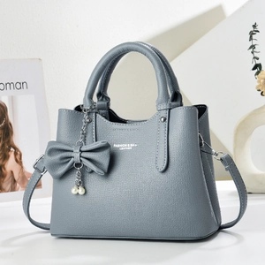 Detailed view of litchi grain leather bag with ribbon bow and pearl charm accessories