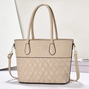 Détail du sac cabas en cuir matelassé beige avec logo métallique en forme de noeud