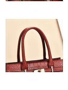 Détail du fermoir doré et de la texture crocodile sur un sac à main marron rouge