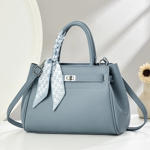 Detail of light blue lychee pattern handbag with silver lock and decorative silk scarf