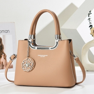 Detail of camel lychee leather bag featuring a silver U-shaped handle and floral charm