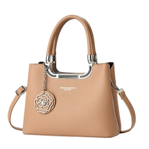 Khaki pebbled leather handbag with metal U-handles and floral pendant on white background