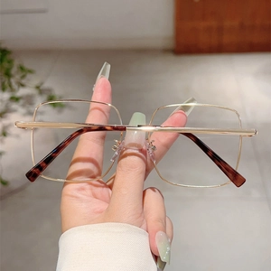 Gros plan détaillé de la monture de lunettes carrée en métal doré avec bouts écaille