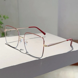 Détail de monture de lunettes carrée en métal doré avec des accents rouges vifs