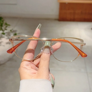 Detailed view of cat-eye gold metal frames with transparent lenses and orange temple tips