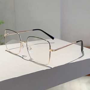Vue détaillée des lunettes dorées à monture carrée avec embouts de branches noirs chic
