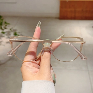 Detailed macro view of rose gold cat-eye metal frame with spring hinges and clear lenses