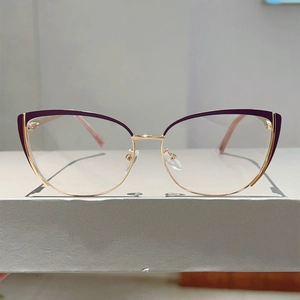 Macro shot of cat eye glasses showing purple frame and gold metal spring hinge details