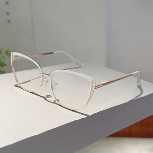 Detail of white cat-eye glasses frame with golden metal spring hinges and nose bridge