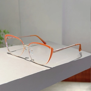 Close-up of cat-eye glasses with orange and gold frames and thin metal spring legs