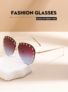 Detail of pilot sunglasses featuring gradient blue lenses with gold rivet trim on stone