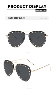 Close-up of pilot sunglasses with gold metal frame and black lenses with gold rivets