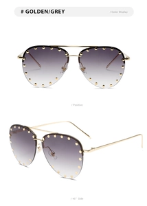 Close-up of golden aviator sunglasses with studded grey gradient lenses and metal frame