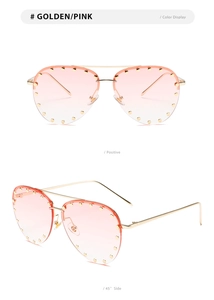 Close-up of golden aviator sunglasses with pink gradient lenses and metal rivets