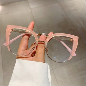 Detail of pink cat-eye frame glasses with gold metal accents held against marble background