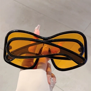 Detail of Y2K shield sunglasses with thick black frame and amber translucent lenses