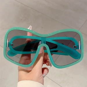 Close-up of mint green oversized Y2K shield sunglasses with thick frames and dark lenses