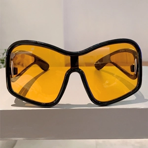 Detail of Y2K shield sunglasses featuring oversized black frames and yellow lenses