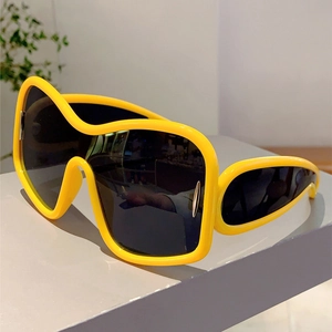 Detail of yellow wrap-around sunglasses with silver metal trim and Y2K futuristic shield lens
