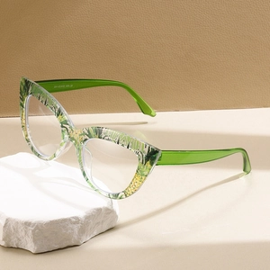 Lunettes œil-de-chat avec monture à motif floral vert sur une pierre décorative blanche