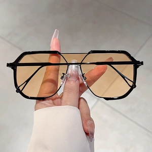 Detail of trendy oversized geometric sunglasses with orange lenses and metal top bar