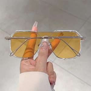 Close-up of oversized square sunglasses with orange lenses and silver metal temples