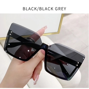 Detail of rimless square sunglasses with glossy black frames and silver metal rivets
