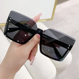 Handheld view of oversized rimless square sunglasses with dark lenses and wide black temples