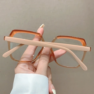 Detail of square two-tone fashion glasses with orange and beige frame hand-held display