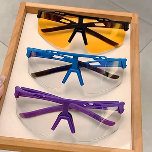 Lunettes de soleil cyclisme avec montures noires, bleues et violettes sur plateau bois