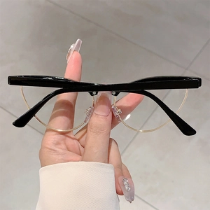 Detailed view of retro black and gold semi-rimless cat-eye glasses held by hand