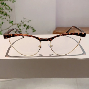 Close-up of tortoise shell cat-eye glasses with gold metal accents on a grey stand