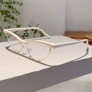 Detail of cat eye glasses with cream white frame and golden metal rim on a stand