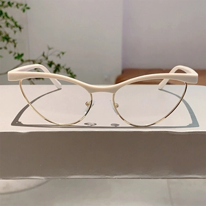 Detail of cream and gold cat-eye glasses frame with sleek metallic rim and elegant finish