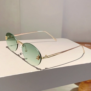 Dettaglio di lenti sfumate verde chiaro senza montatura con strass a forma di lettera F