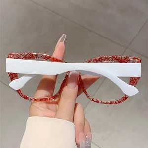 Detail of red marbled pattern on large transparent frame eyeglasses held in hand