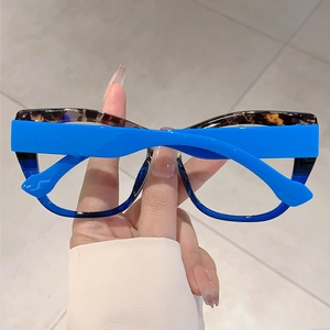 Detail of oversized glasses with bold royal blue frames and tortoiseshell accents