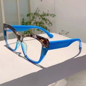 Detailed view of cat-eye blue glasses with tortoiseshell pattern on white stand