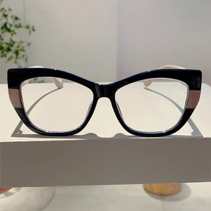 Detailed side view of two-tone cat-eye glasses frame with pink accents on a white stand