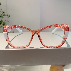 Detail view of cat-eye glasses with red abstract texture and white temples on a stand