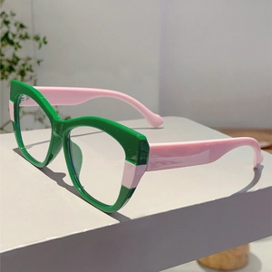Detail view of bold green cat-eye frames with pink temples on a minimalist display stand