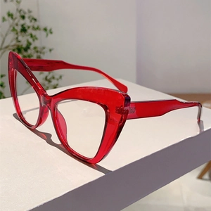 Close-up of vintage cat-eye eyeglasses with transparent red resin frames on a white stand