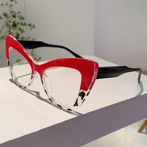Detail of red and leopard cat-eye glasses frame on white stairs with green leaves